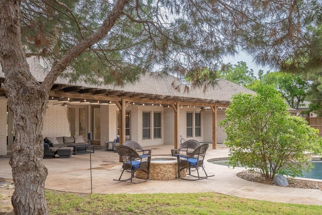 4508 Island Dr, Midland, TX 79707 - rear view of property featuring an outdoor living space with a fire pit, brick siding, a pergola, a patio area, and a shingled roof