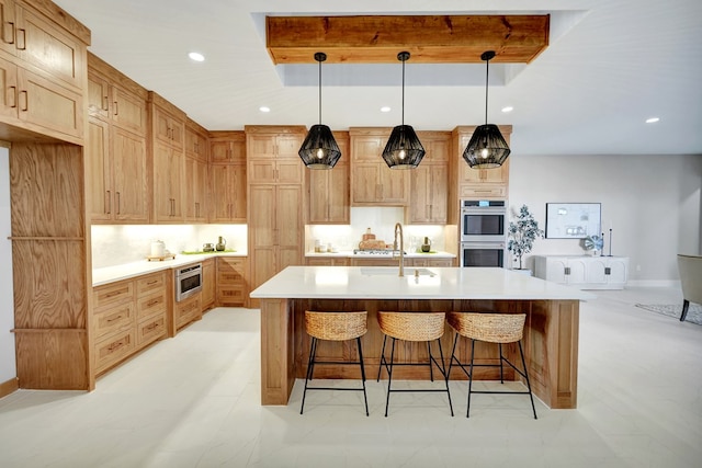 kitchen with sink, decorative light fixtures, a center island with sink, appliances with stainless steel finishes, and decorative backsplash