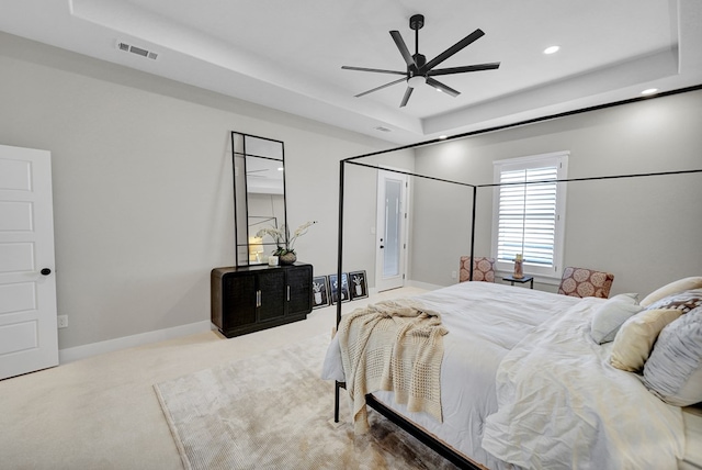 bedroom with a raised ceiling, carpet floors, and ceiling fan