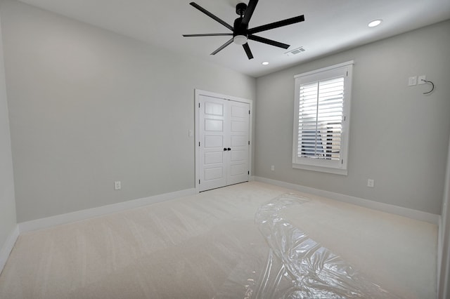 unfurnished bedroom featuring ceiling fan, light colored carpet, and a closet