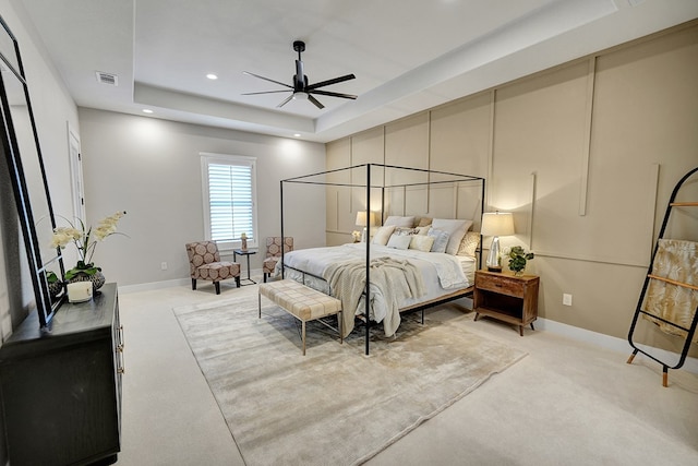 carpeted bedroom featuring a raised ceiling and ceiling fan