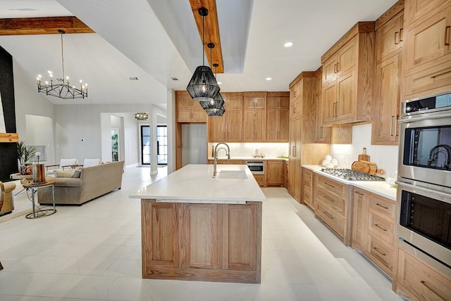 kitchen featuring sink, appliances with stainless steel finishes, hanging light fixtures, an island with sink, and decorative backsplash