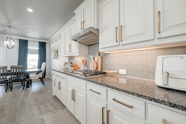 9 Senita Ct, Odessa, TX 79765 - kitchen featuring under cabinet range hood, baseboards, white cabinetry, a chandelier, and stainless steel gas stovetop