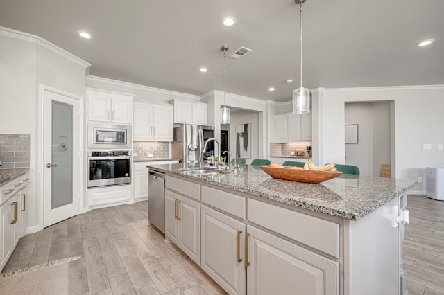 9 Senita Ct, Odessa, TX 79765 - kitchen featuring stainless steel appliances, a sink, backsplash, ornamental molding, and light wood finished floors