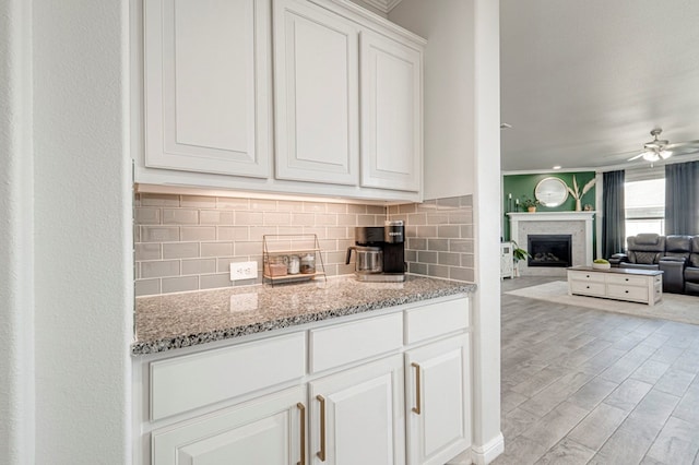 9 Senita Ct, Odessa, TX 79765 - kitchen featuring tasteful backsplash, light stone countertops, ceiling fan, white cabinets, and crown molding