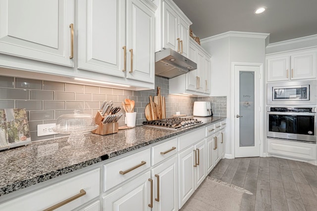 9 Senita Ct, Odessa, TX 79765 - kitchen with appliances with stainless steel finishes, under cabinet range hood, ornamental molding, white cabinetry, and dark stone counters