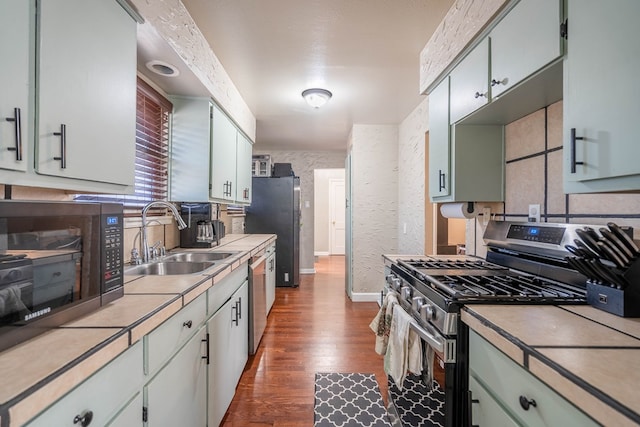 807 Boyd Ave, Midland, TX 79705 - kitchen featuring appliances with stainless steel finishes, a sink, baseboards, light countertops, and dark wood-type flooring