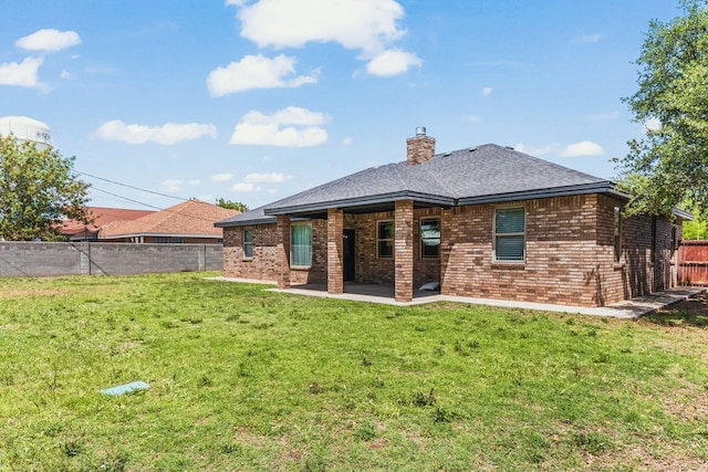rear view of house featuring a patio area, a chimney, brick siding, and a shingled roof