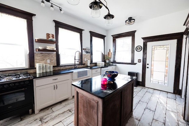 2306 32nd St, Snyder, TX 79549 - kitchen featuring white cabinets, sink, decorative backsplash, black gas range oven, and a kitchen island