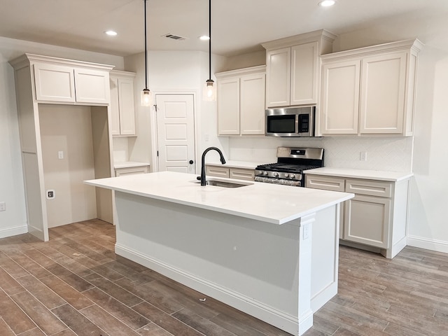 kitchen featuring hanging light fixtures, sink, appliances with stainless steel finishes, and an island with sink