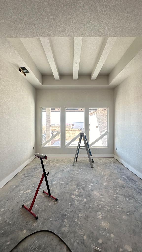 spare room featuring beamed ceiling and a textured ceiling