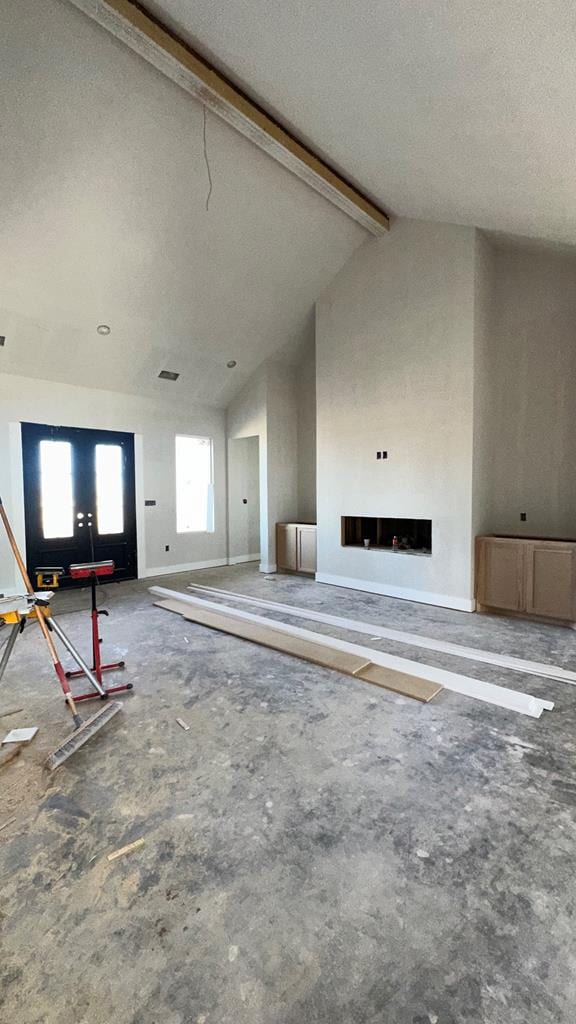 unfurnished living room with a textured ceiling and vaulted ceiling with beams