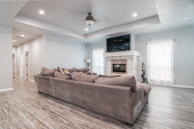 living room featuring hardwood / wood-style floors, ceiling fan, and a raised ceiling