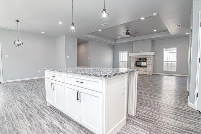 kitchen with a center island, pendant lighting, white cabinets, and a tray ceiling