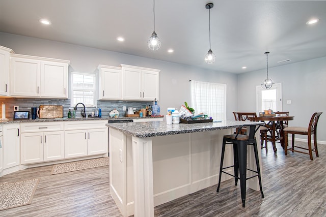 kitchen featuring white cabinetry, decorative light fixtures, a wealth of natural light, and a center island