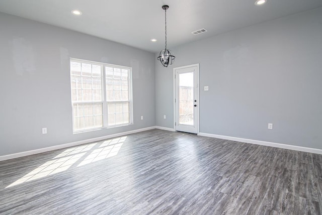 spare room with dark hardwood / wood-style floors and a chandelier