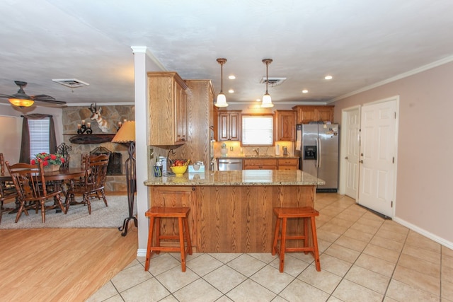 kitchen with crown molding, ceiling fan, a breakfast bar, stainless steel appliances, and a peninsula