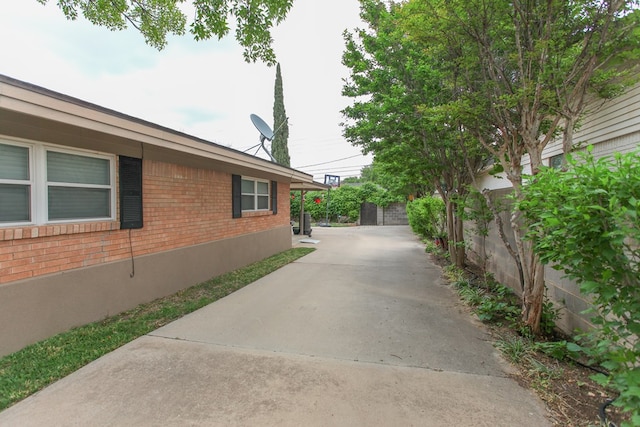 view of side of home with brick siding, fence, and driveway