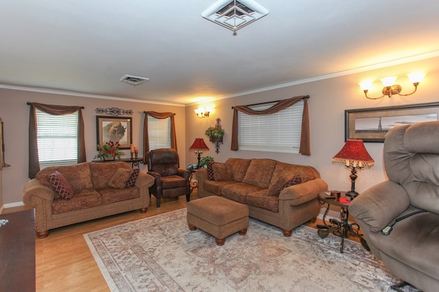 living area featuring baseboards, visible vents, ornamental molding, and wood finished floors