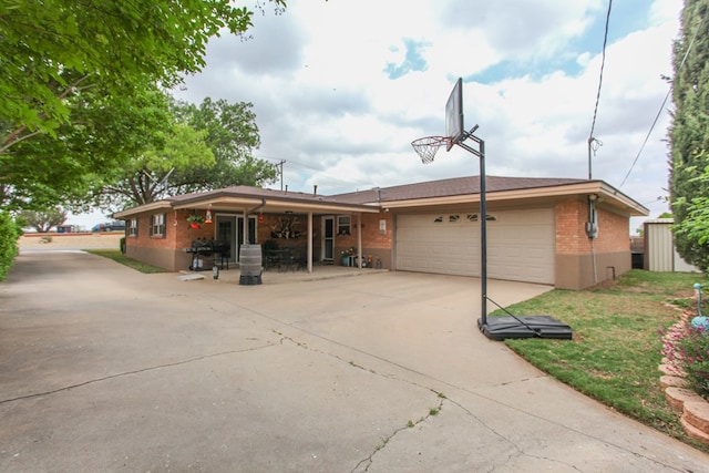 rear view of house with a yard, a garage, brick siding, an outdoor structure, and concrete driveway