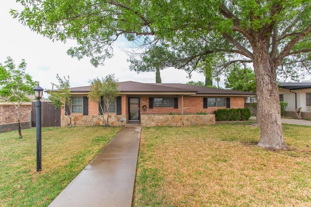 single story home with a front lawn, fence, and stone siding
