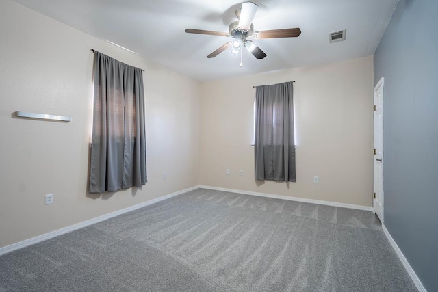 carpeted spare room with baseboards, visible vents, and a ceiling fan