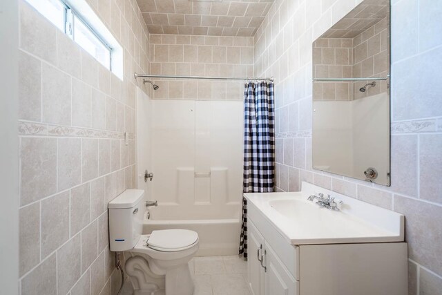 bathroom featuring tile patterned floors, toilet, vanity, shower / bath combo, and tile walls