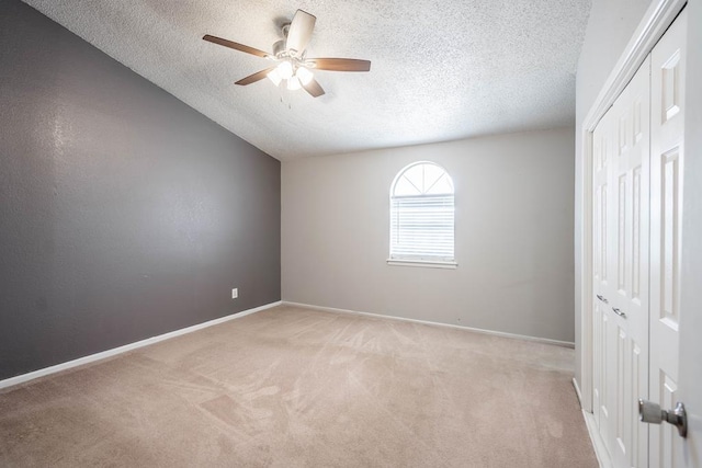 unfurnished bedroom with light carpet, baseboards, a closet, and a textured ceiling