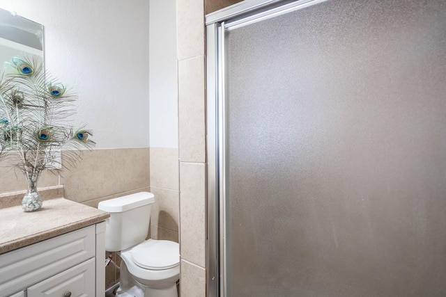 full bath featuring tile walls, toilet, vanity, and a shower stall