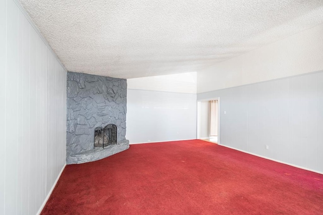 unfurnished living room with lofted ceiling, a textured ceiling, carpet, and a stone fireplace