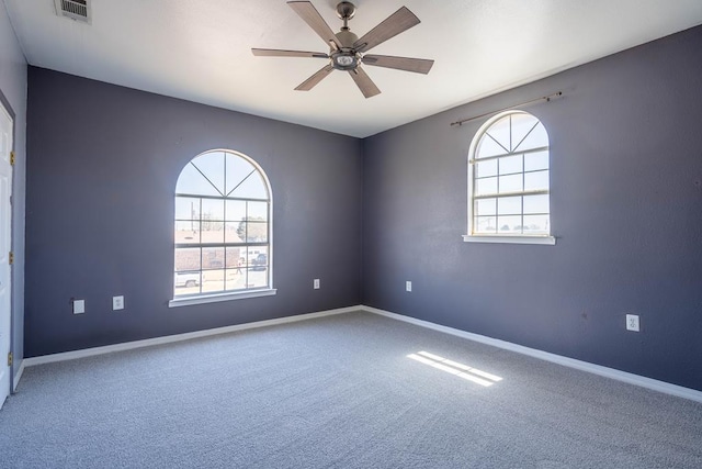 spare room with carpet flooring, a healthy amount of sunlight, ceiling fan, and visible vents