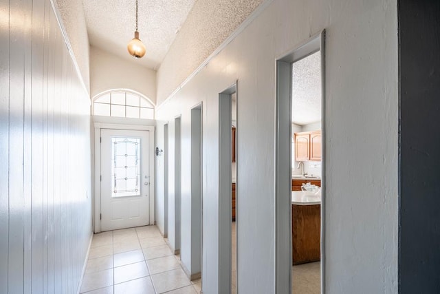 interior space with light tile patterned floors, a sink, vaulted ceiling, and a textured ceiling