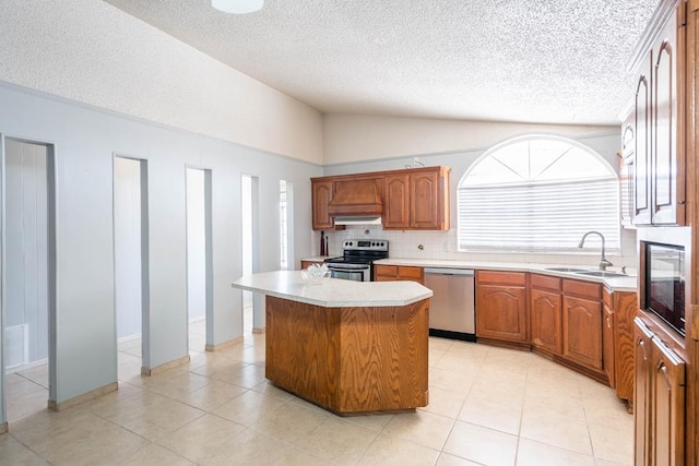 kitchen with light countertops, stainless steel appliances, a sink, vaulted ceiling, and a center island