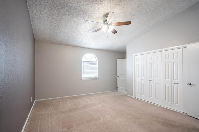unfurnished bedroom featuring a closet, a textured ceiling, carpet, baseboards, and ceiling fan