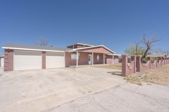 view of front facade featuring brick siding, driveway, fence, and an attached garage