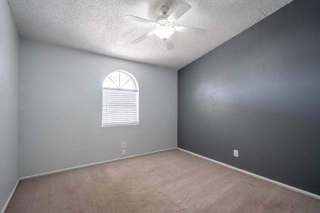 empty room featuring a textured ceiling, baseboards, carpet flooring, and a ceiling fan
