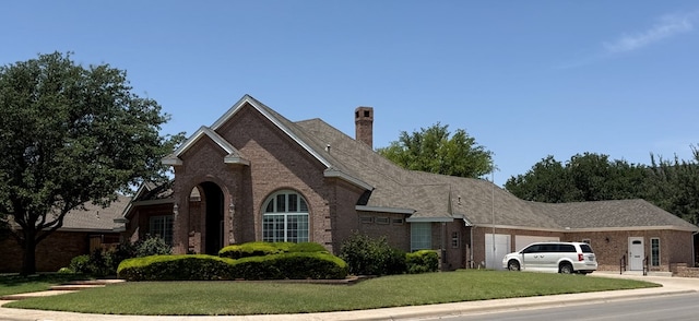 4000 Baybrook Dr, Midland, TX 79707 - view of front of property with brick siding, a front lawn, an attached garage, a chimney, and concrete driveway