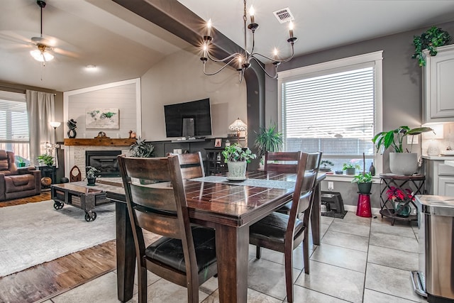 tiled dining area featuring a wealth of natural light, lofted ceiling, and ceiling fan with notable chandelier