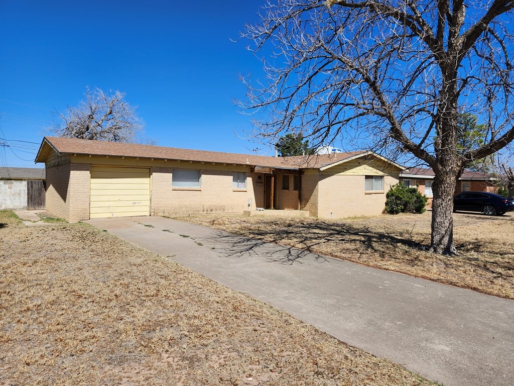 ranch-style home featuring a garage, concrete driveway, and brick siding