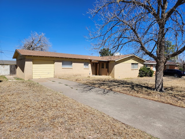 ranch-style home featuring a garage, concrete driveway, and brick siding