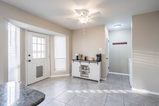 entryway featuring light tile patterned floors, ceiling fan, and baseboards