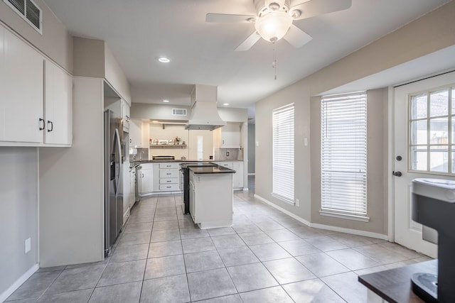 kitchen with light tile patterned floors, visible vents, dark countertops, island exhaust hood, and open shelves