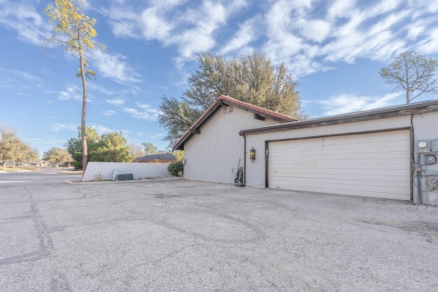 view of side of property featuring a garage and stucco siding