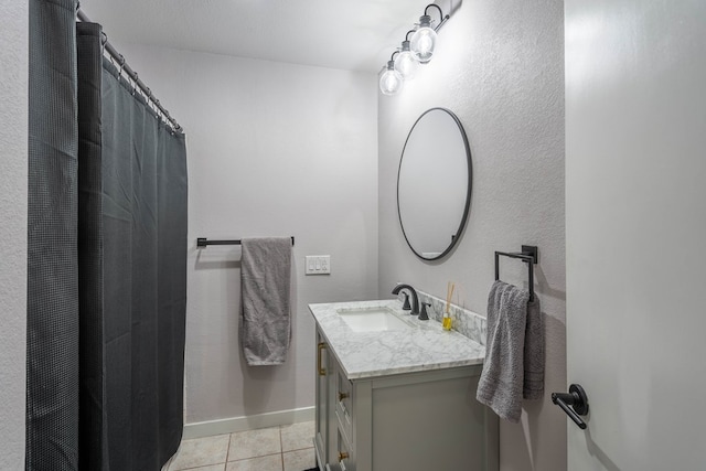 full bath with baseboards, vanity, and tile patterned floors