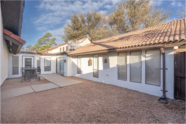 back of house featuring stucco siding, a tile roof, and a patio