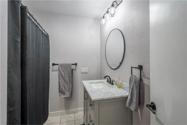 bathroom featuring curtained shower, tile patterned flooring, baseboards, and vanity