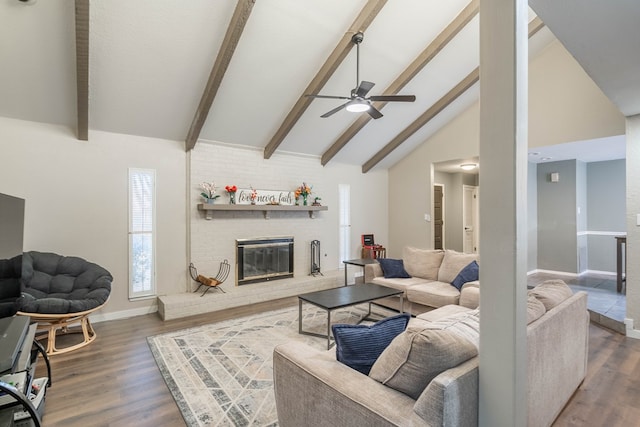 living area featuring a brick fireplace, beamed ceiling, baseboards, and wood finished floors