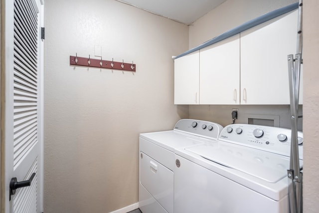 washroom featuring washing machine and clothes dryer, cabinet space, and baseboards