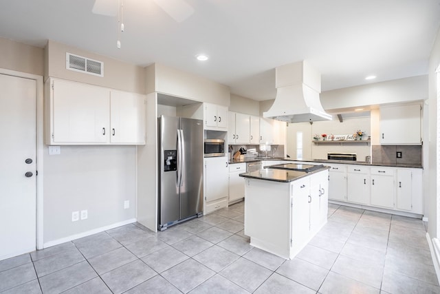 kitchen with visible vents, dark countertops, a kitchen island, island exhaust hood, and stainless steel appliances