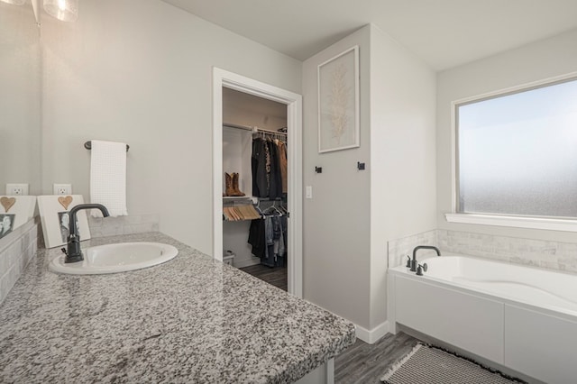 bathroom with hardwood / wood-style flooring, vanity, and a tub to relax in